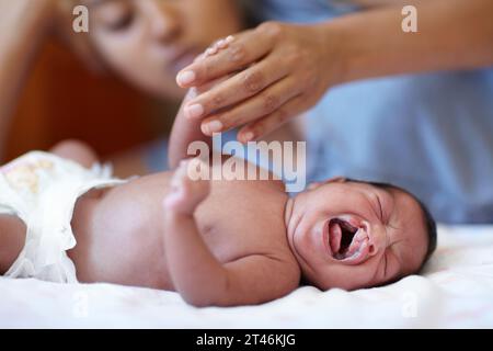 Nouveau-né, pleurs et fente palatine avec maman, lit et main tenant avec le parent, malade et la maison familiale. Problème médical, syndrome et chambre à coucher pour les soins de santé Banque D'Images