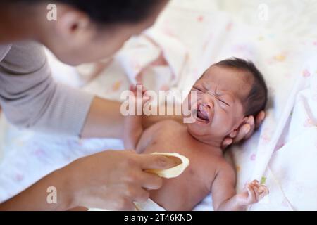 Nouveau-né, pleurs et fente palatine avec nettoyage, maman et lit avec parent, malade et frustré. Problème médical, syndrome et chambre à coucher à domicile pour les soins de santé Banque D'Images