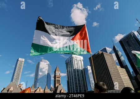 Toronto, Canada - 28 octobre 2023 : le drapeau palestinien flotte haut au milieu de l'horizon de la ville, avec des gratte-ciel et une vieille tour d'horloge debout dans le Banque D'Images