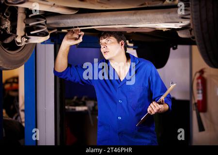 Voiture, inspection ou entretien avec un mécanicien dans un garage pour un rapport sur une réparation de véhicule pour assurance. Service, professionnel et expertise Banque D'Images