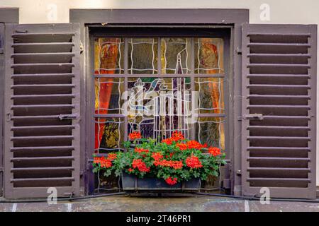 Vitrail orné avec volets en bois et fleurs sur une maison traditionnelle à colombages dans le centre historique de Strasbourg, Alsace, France Banque D'Images