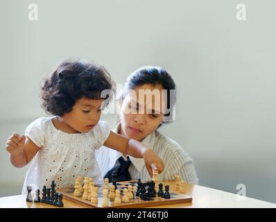 Mère, enfant et jeu d'échecs pour la croissance de l'apprentissage, le défi de développement ou le temps de liaison. Fille, femme ou jeu de société amusant pour la résolution de problèmes Banque D'Images