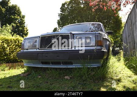 Vue de face d'une Volvo 700 ancienne et abandonnée stationnée sur l'herbe, près d'une clôture en bois, dans la banlieue de Melbourne Banque D'Images