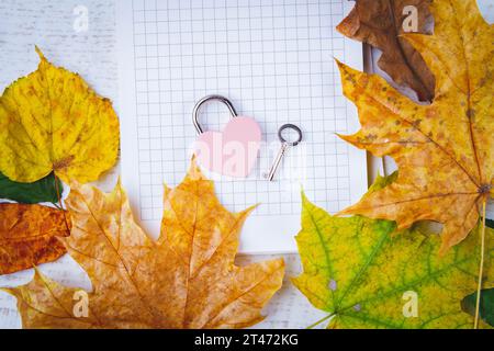 Message d'amour dans les feuilles d'automne. Nettoyez l'ordinateur portable et le verrou en forme de cœur sur fond blanc. CopySpace... Banque D'Images