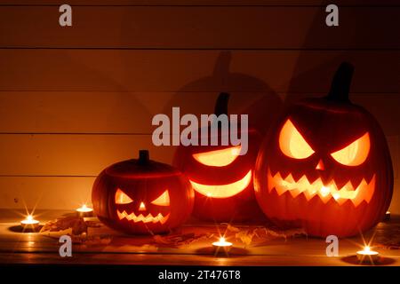 Trois lanternes de citrouille d'Halloween et bougies allumées sur fond de bois foncé Banque D'Images