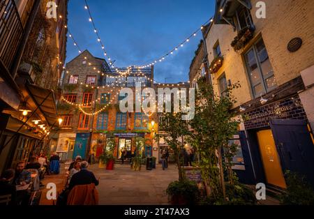 Londres, Royaume-Uni : Neal's Yard dans le quartier de Covent Garden au centre de Londres. Les gens assis à l'extérieur d'un restaurant le soir. Banque D'Images