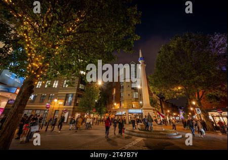 Londres, Royaume-Uni : rond-point Seven Dials dans le quartier de Covent Garden au centre de Londres. Les gens marchent dans la rue la nuit. Banque D'Images