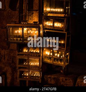 Des menorahs de Hanukkah incandescents portant les mots hébreux « ces bougies, elles sont sacrées », avec de petites fioles d'huile brûlent dans un boîtier en verre protecteur Banque D'Images