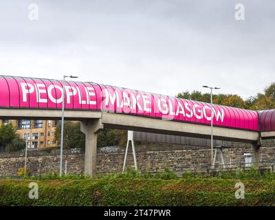 Les gens font le signe de bannière de slogan Glasgow sur la passerelle du tunnel de la ville Banque D'Images