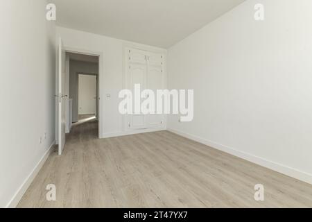 Chambre vide dans une maison avec des murs peints en blanc, des planchers en bois clair, une belle armoire intégrée Banque D'Images