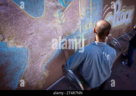 Los Angeles, États-Unis. 28 octobre 2023. Un homme utilise la craie pour exprimer ses souhaits de paix entre Israël et la Palestine lors d'un rassemblement dans la DTLA le samedi 28 octobre. Crédit : SIPA USA/Alamy Live News Banque D'Images