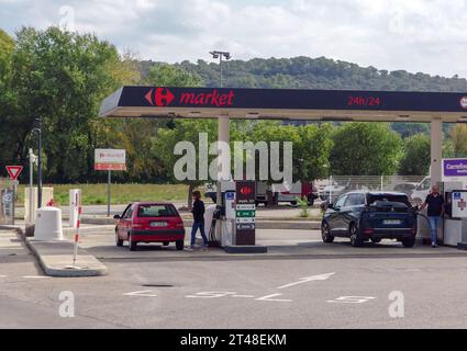 Un homme et une femme faisant le plein de voitures dans une station-service à Bagnols-sur-Cèze, dans l'est du Gard, France. Banque D'Images