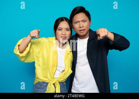 Confus triste couple asiatique sérieux dans les doigts de pointage occasionnels à la caméra Banque D'Images