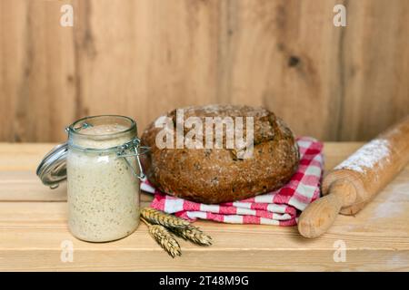 levain, pain, rouleau à pâtisserie et épis de blé sur fond en bois, se concentrer sur la levure Banque D'Images