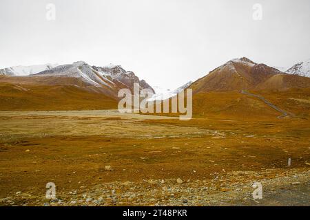 Col de Khunjerab près de la frontière Pakistan-Chine, saison d'automne. Couleurs d'automne jaune et orange et montagnes Karakoram couvertes de neige. Banque D'Images