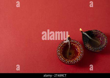 Joyeux Diwali et Kartika Deepam Festival Salutations - lampe colorée de diya d'argile sur fond rouge Banque D'Images