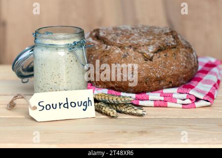 étiquette de levain avec pot de levure, pain, épis de blé sur fond en bois Banque D'Images