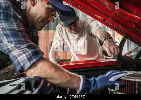 Deux passionnés de muscle Cars classiques caucasiens travaillant sur le moteur de voiture Banque D'Images