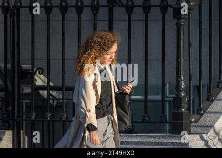 La vie quotidienne. Jeune femme stylée dans la ville avec son téléphone portable tout en marchant dans une rue de la ville. Dublin, Irlande. Banque D'Images