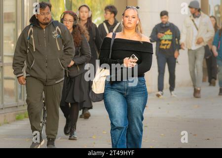 La vie quotidienne. Jeune femme stylée dans la ville avec son téléphone portable tout en marchant dans une rue de la ville. Dublin, Irlande. Banque D'Images