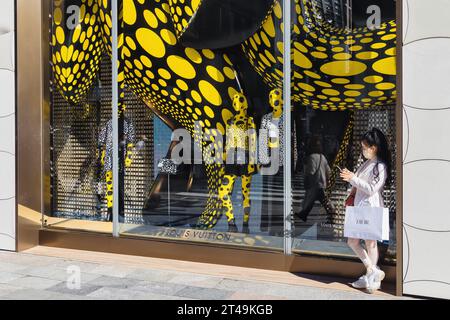 Tokyo, Japon - 10 avril 2023 : vitrine du magasin Louis Vuitton dans le quartier de Ginza avec une femme non identifiée. C'est une maison de mode de luxe française et Banque D'Images