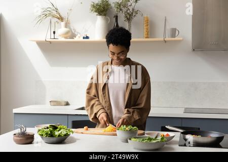 Heureuse fille de chef afro-américaine cuisinant un dîner sain Banque D'Images