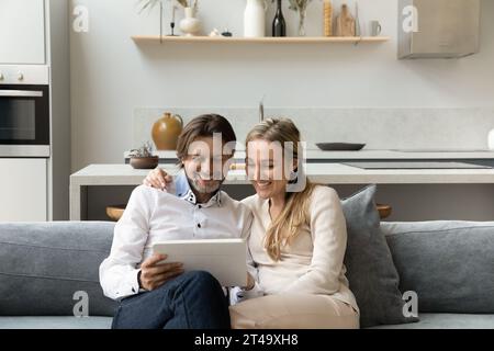 Joyeux couple en utilisant l'application en ligne sur l'ordinateur tablette numérique Banque D'Images