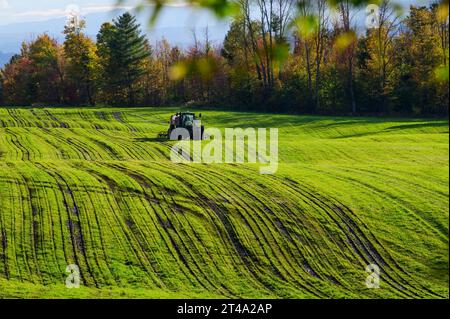 Tracteur et équipement agricole travaillant sur un champ d'automne vert dans les Green Mountains du Vermont. Banque D'Images