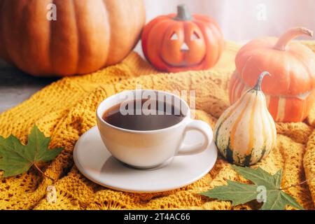 Citrouilles, tasse à café et décorations d'Halloween sur chandail jaune. Nature morte d'automne, concept de Thanksgiving. Gros plan. Banque D'Images