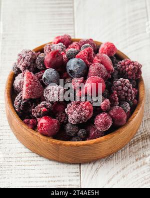 Baies assorties congelées dans un bol en bois sur fond blanc. Baies, aliments surgelés. Banque D'Images