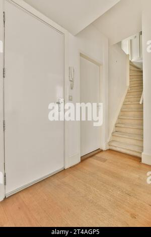 une pièce vide avec des murs blancs et du parquet sur le côté droit, il y a un escalier menant au deuxième étage Banque D'Images