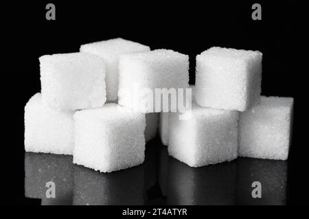 Cubes de sucre raffiné blanc dans un tas sur un fond sombre avec réflexion Banque D'Images