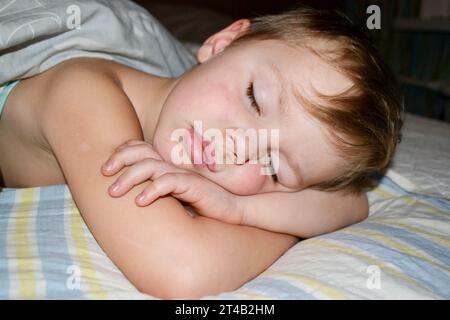 Enfant de cinq ans dormant dans le lit sur un oreiller avec une girafe en peluche. Photo de haute qualité Banque D'Images