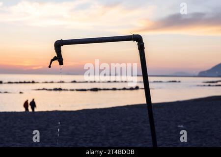 Douche goutte à goutte au coucher du soleil sur la plage, Marina di Massa, Toscane, Italie Banque D'Images