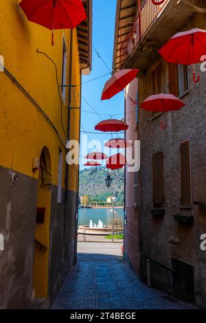 City Street à Porto Ceresio avec parasols suspendus avec vue sur le lac dans une journée d'été ensoleillée à Porto Ceresio, Lombardie, Italie Banque D'Images