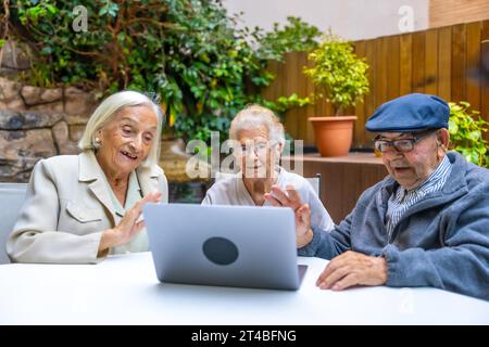 Personnes âgées brandissant pendant un appel vidéo avec un ordinateur portable chez un gériatrique Banque D'Images