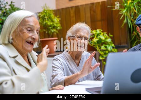 Femmes heureuses brandissant lors d'un appel vidéo chez un gériatre. Introduction de la technologie aux aînés Banque D'Images