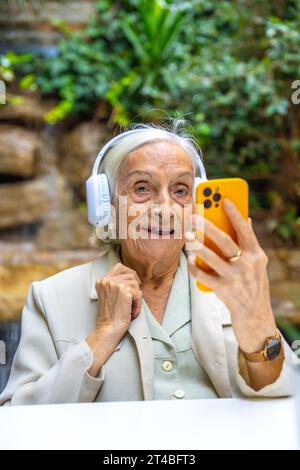 Portrait vertical d'une femme aînée écoutant de la musique au téléphone chez un gériatrique Banque D'Images