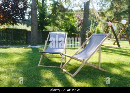 Chaises longues dans le jardin, à l'ombre sous les arbres. Mobilier de jardin extérieur. Banque D'Images