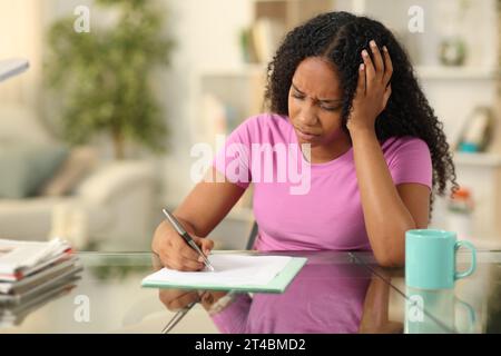 Femme noire triste signant la forme se plaignant à la maison Banque D'Images