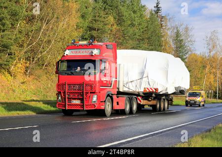 Rouge Volvo FH camion remorque à plateau M Nikkanen Ky transporte une large charge. Le transport dispose de 3 véhicules pilotes à l'avant et à l'arrière. Raasepori, Finlande. 13 octobre 23 Banque D'Images