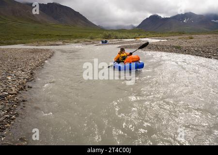 Femme flottant sur une rivière dans un tout petit radeau dans le parc national Denali, Alaska. Banque D'Images