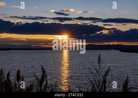 Le soleil se couche sur l'extrémité sud d'Antelope et se reflète sur les eaux de l'unité Turpin de Farmington Bay WMA, Farmington, Utah, USA. Banque D'Images