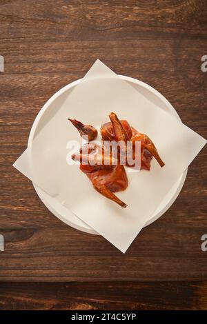 Pigeon cantonais traditionnel grillé sur une assiette en porcelaine blanche，pigeon croustillant Banque D'Images