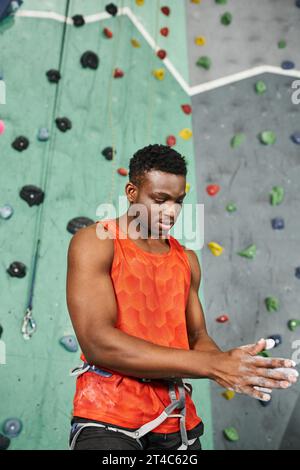 plan vertical d'un homme afro-américain musclé utilisant de la craie de gym avec mur de blocs en toile de fond Banque D'Images