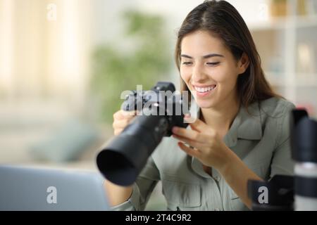 Photographe heureux à la maison vérifiant le résultat sur l'appareil photo sans miroir Banque D'Images