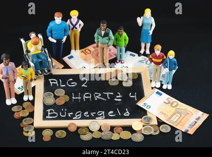 Bénéficiaires de l'aide sociale debout autour d'un tableau noir lettrage ALG 2, Hartz 4, Buergergeld - dividende citoyen Banque D'Images