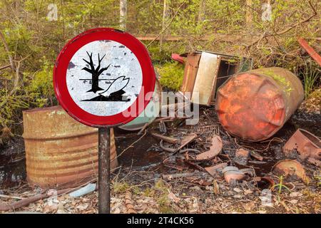 Panneau d'avertissement devant les barils de déchets toxiques laissés dans une forêt Banque D'Images