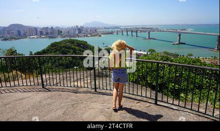 Tourisme au Brésil. Vue panoramique de jeune femme voyageur profitant du paysage urbain de Vitoria avec le pont Terceira Ponte, Vitoria, Espirito Santo, Brésil. Banque D'Images