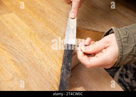 Les mains de la personne travaillent enlever les dommages d'eau du comptoir de matériau de bloc de boucher dans la cuisine à la maison, entretien de bord d'évier. Banque D'Images